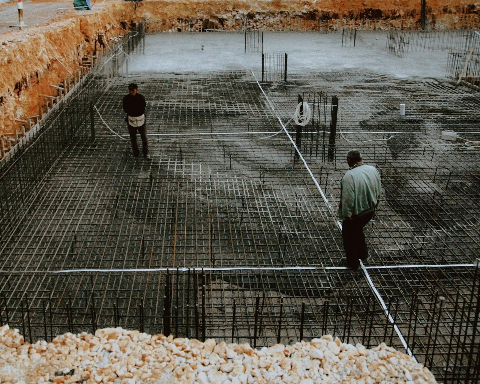 Site workers laying a steel reinforcement grid for a concrete raft