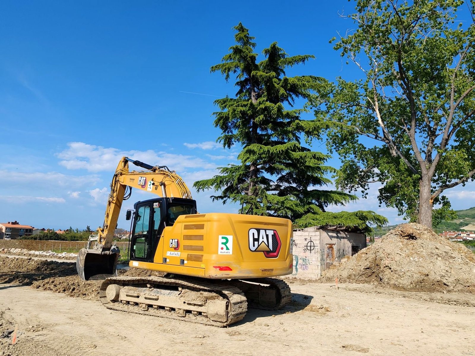 Tracked excavator working on a construction site under a blue sky