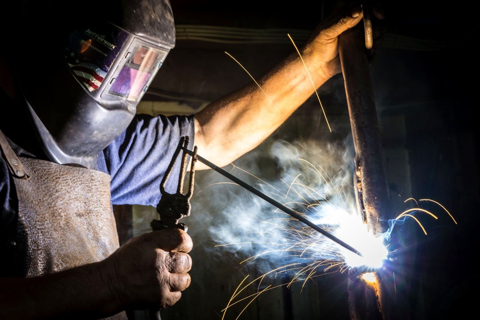 Welder striking an arc on a steel section, sparks flying