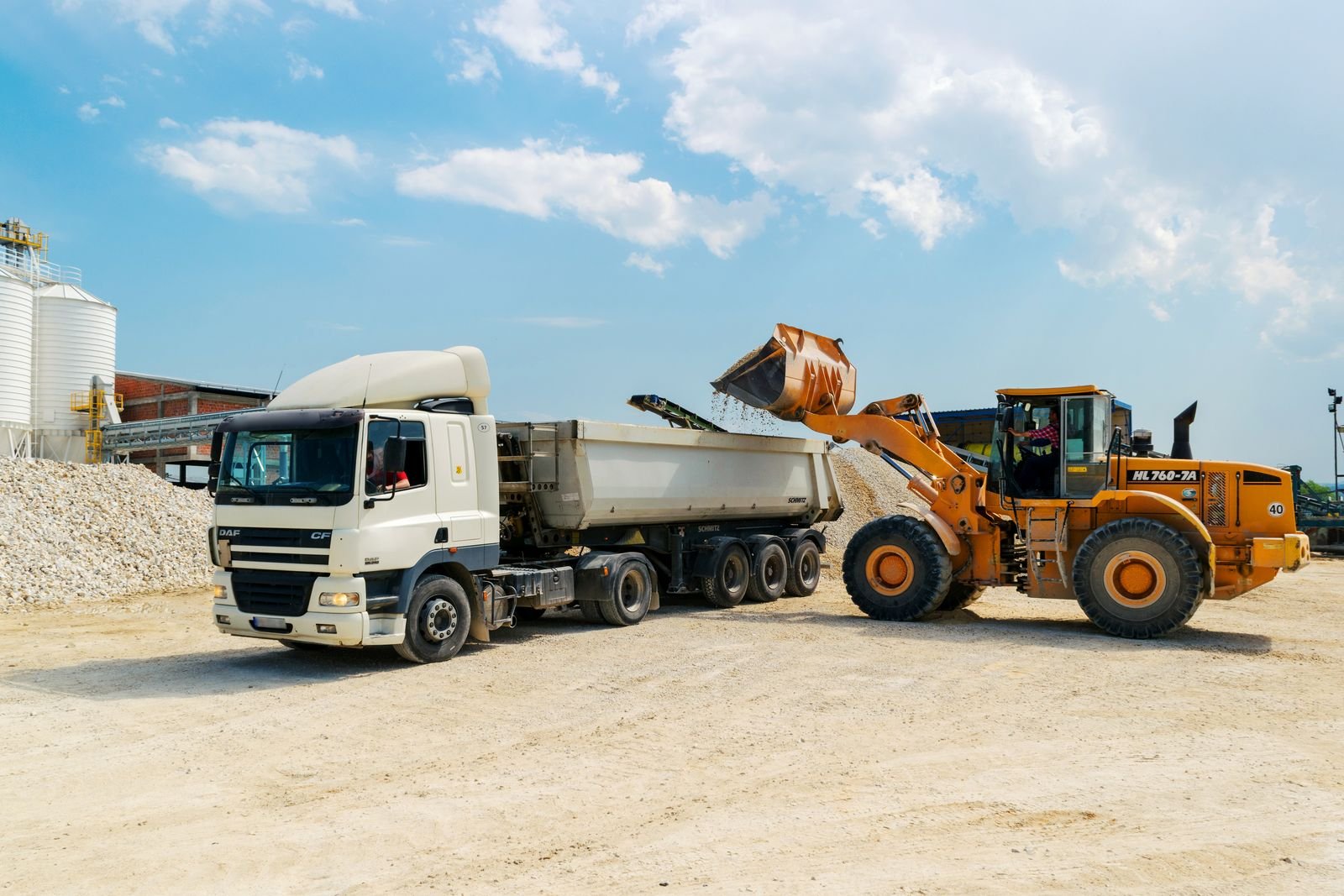 Wheel loader filling a tipper truck with aggregate at a yard