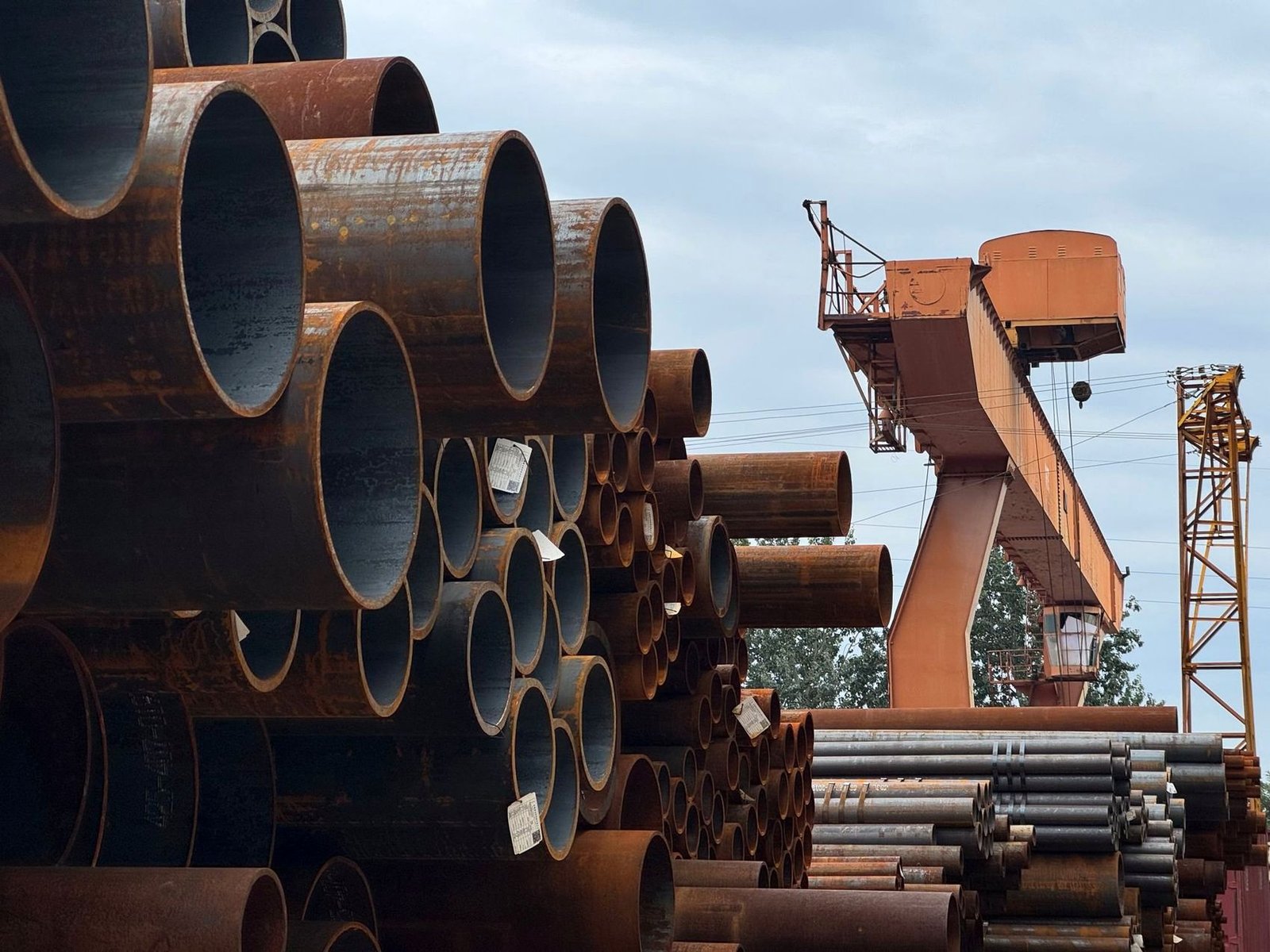 Stacked steel pipe and tube in a supply yard with an overhead gantry crane