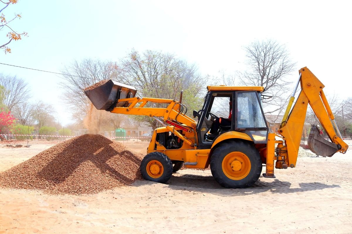 Backhoe loader moving aggregate on a site